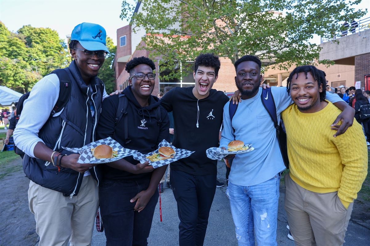 Smiling students carrying food from food trucks.