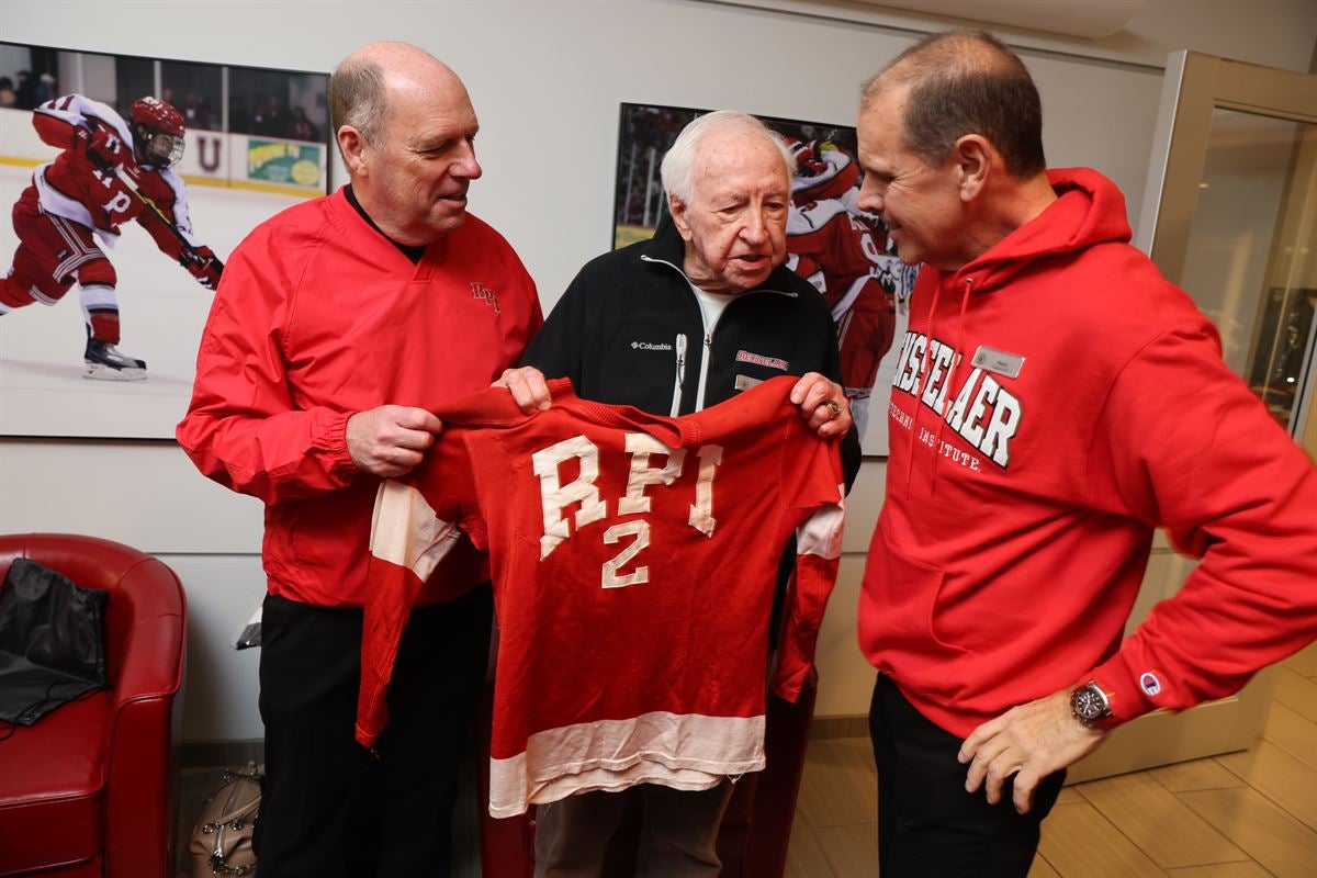 President Marty Schmidt hands hockey jersey to alumnus Lloyd Bauer at the Big Red Freakout.