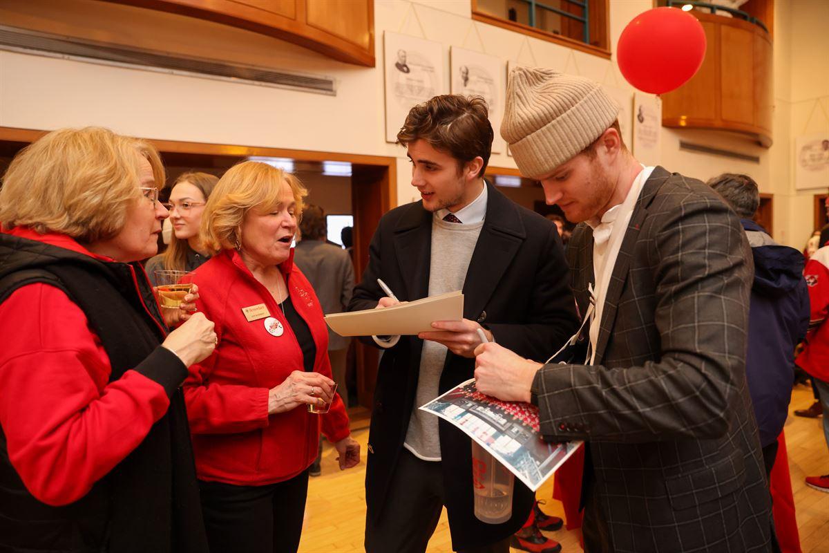 Lyn Schmidt and her sister getting autographs from hockey players at the post-game Big Red Freakout Ice House.