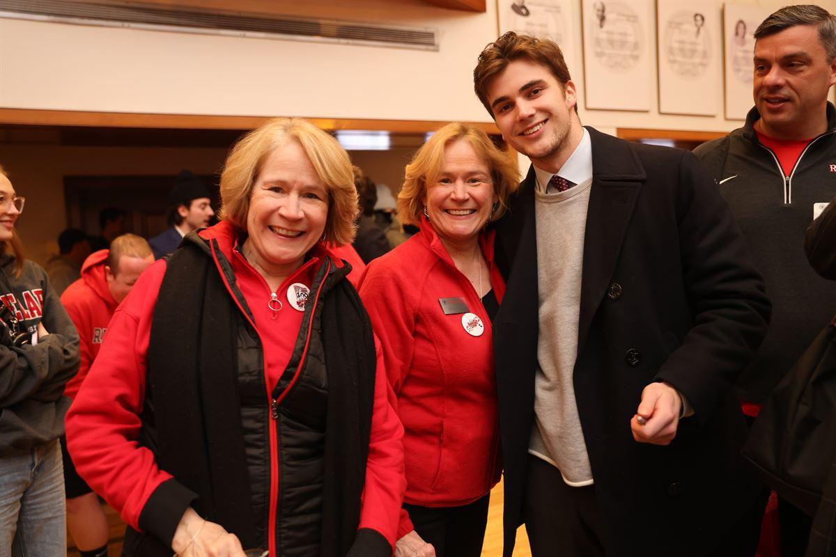 Lyn Schmidt and her sister smiling with a hockey player at the post-game Big Red Freakout Ice House.