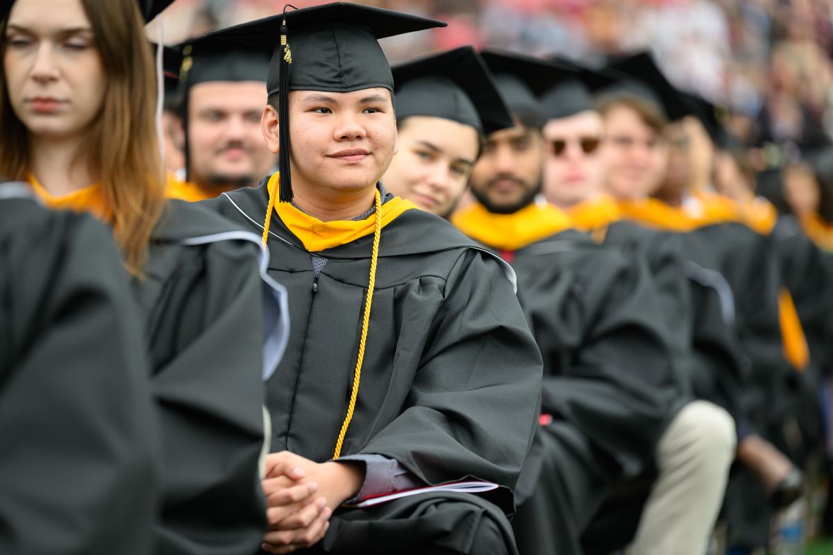 A group of graduates wearing black cap and gowns with yellow hoods at RPI's Commencement ceremony.