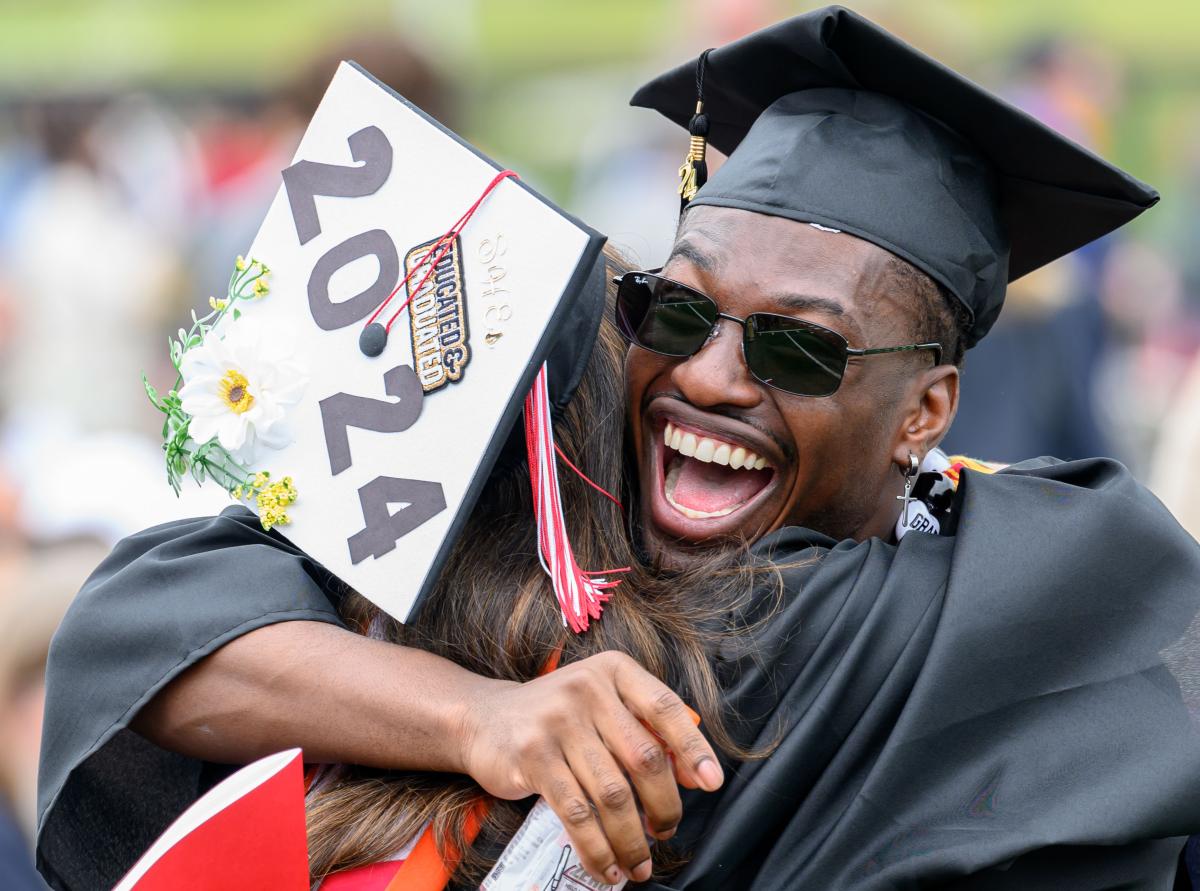 Graduate in cap and gown joyfully hugging another person at RPI's Commencement ceremony.