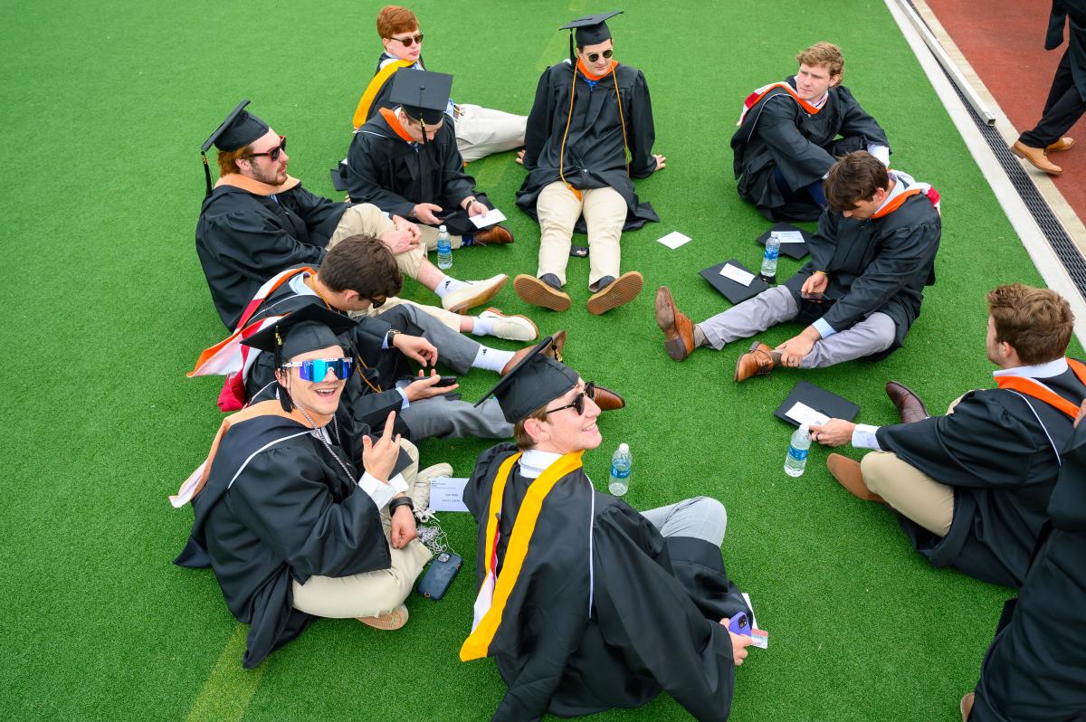 Graduates sitting in a circle on Harness Field ahead of RPI's Commencement ceremony.