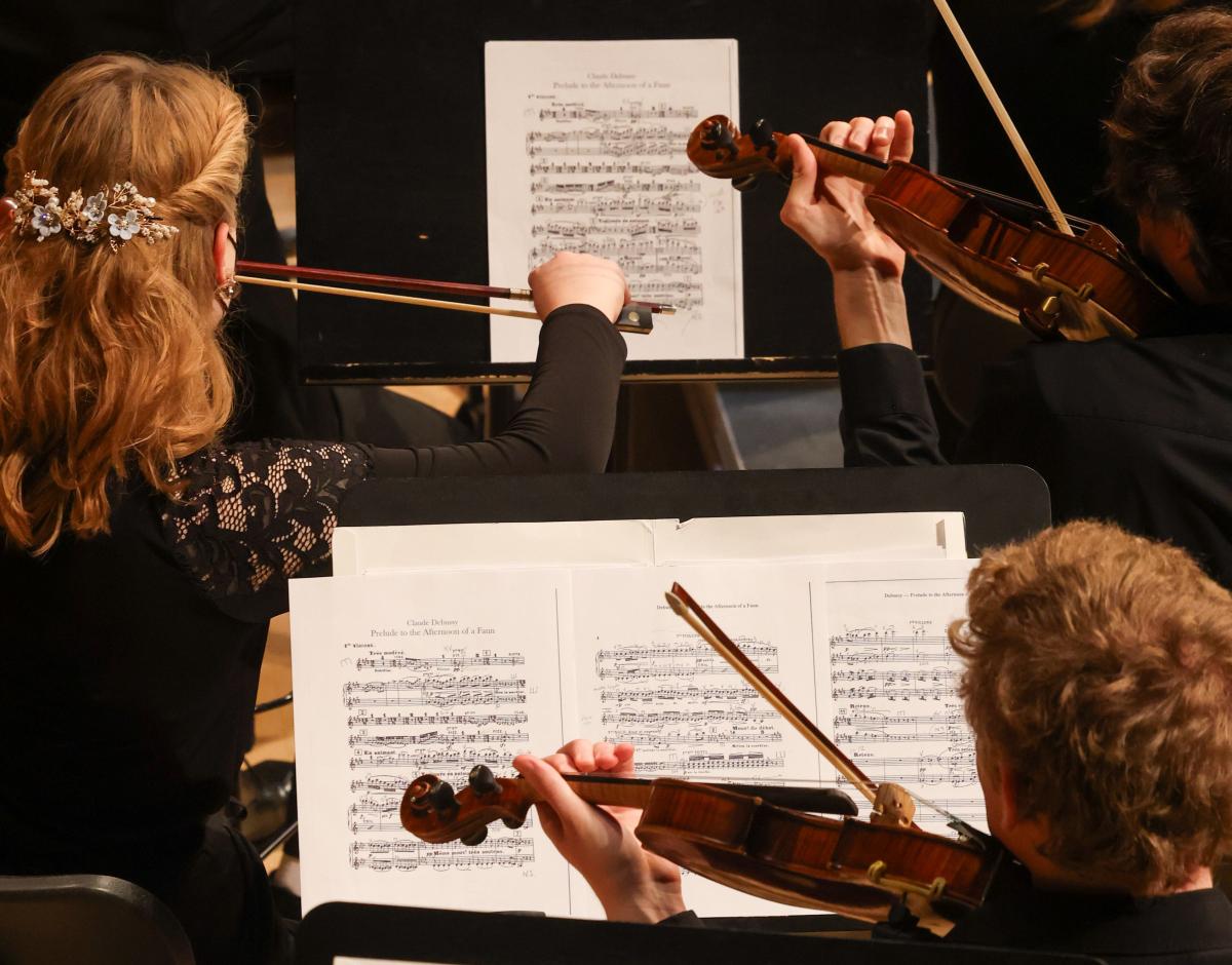 A close-up view of the hands, instruments, and music sheets of three student musicians at RPI's holiday concert.