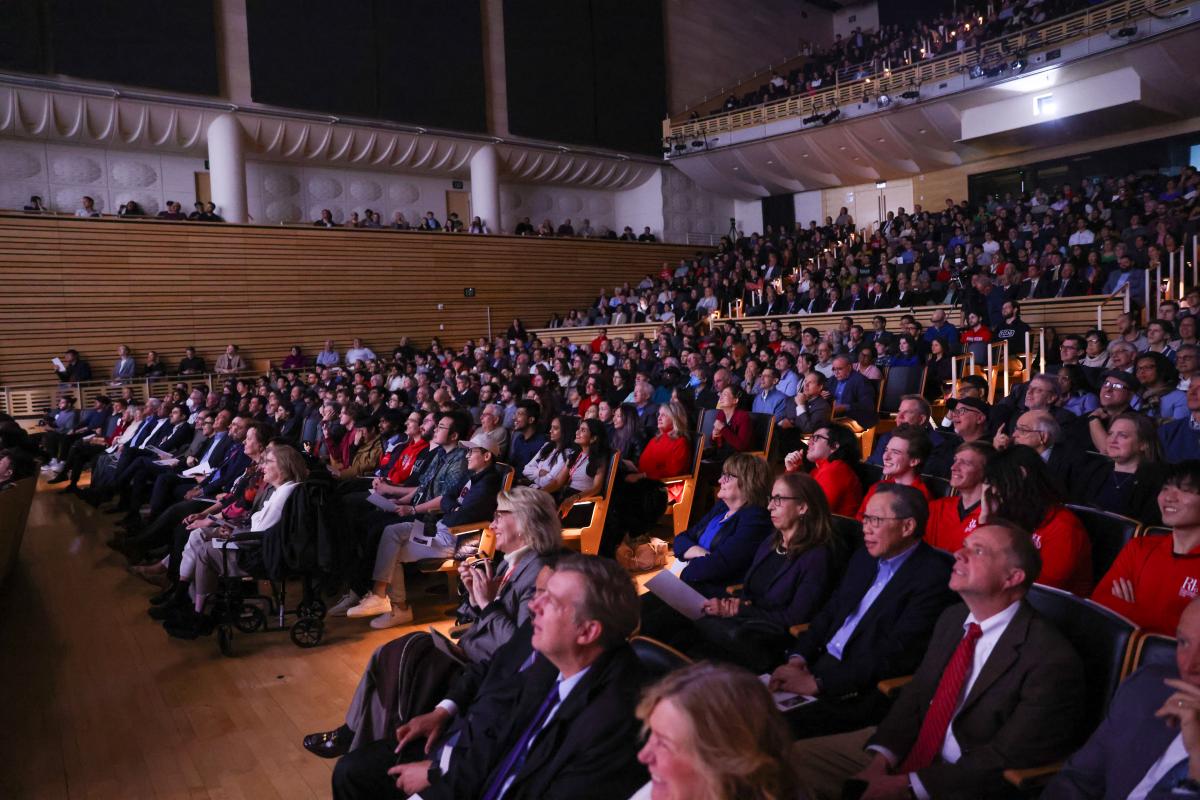 A full audience watches a video during a ceremony celebrating the unveiling of an IBM quantum computer on RPI's campus.